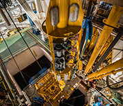 View from above of instruments being lowered to the ocean floor through an opening in the ship.